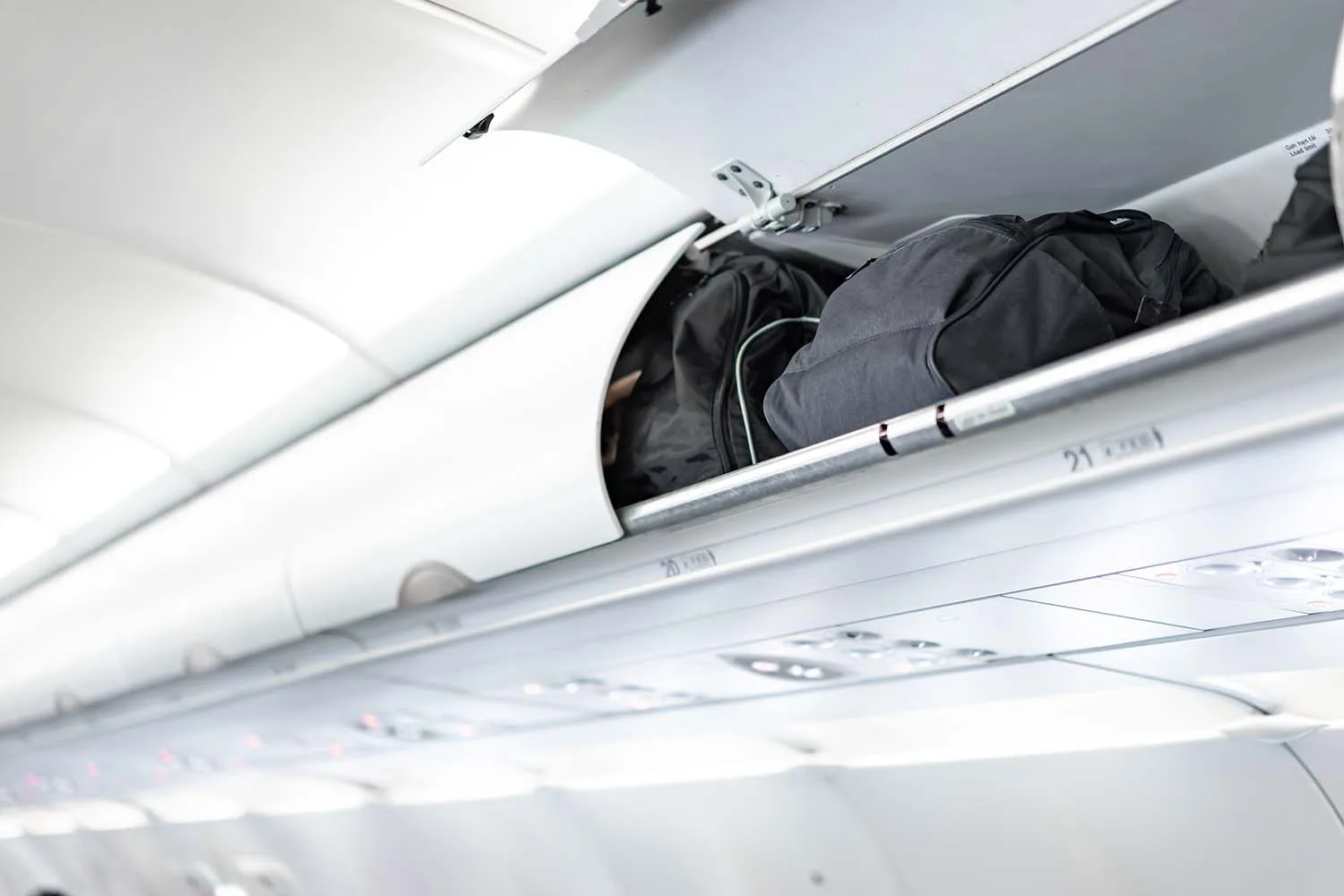 Rugzakken in een bagagevak boven vliegtuigstoelen